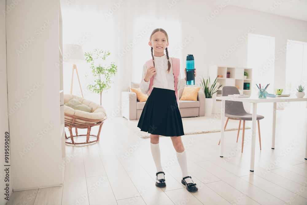 Photo of cute small schoolkid bag bottle water wear uniform living room apartment indoors Photo of cute small schoolkid bag bottle water wear uniform living room apartment indoors