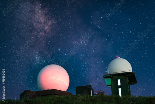 White meteorological radar station with blinking lights set against a deep blue starry sky and a romantic galaxy. Captivating night scene, Wufeng Mountain, Taiwan. photo