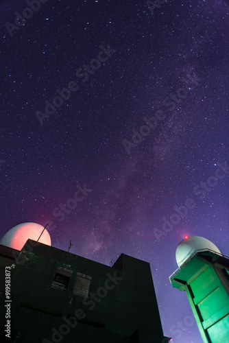 White meteorological radar station with blinking lights set against a deep blue starry sky and a romantic galaxy. Captivating night scene, Wufeng Mountain, Taiwan. photo