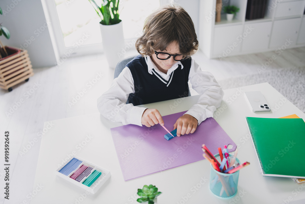 Portrait of cute adorable boy schoolkid sitting table doing homework handicraft lesson course education from home indoors Portrait of cute adorable boy schoolkid sitting table doing homework handicraft lesson course education from home indoors