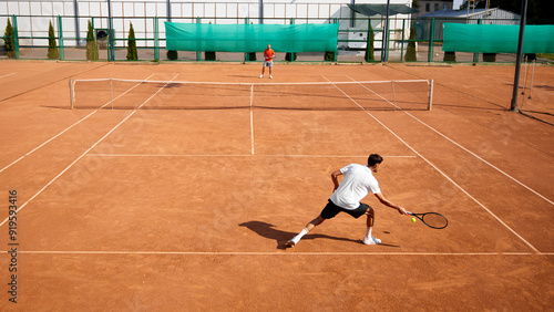 Foto Two male tennis players in action on outdoor clay tennis court, showing skills, focus and endurance during intense training session