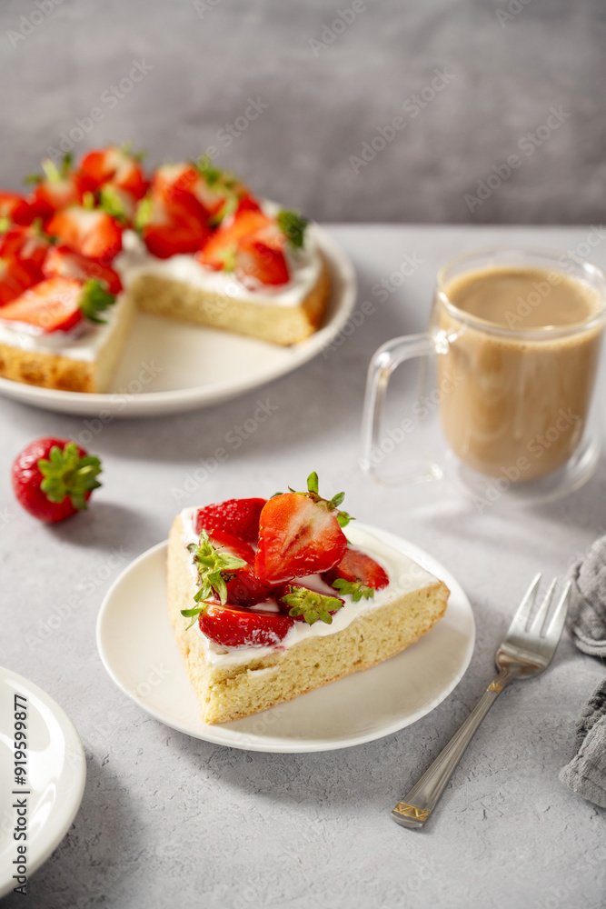 Slice of sponge cake with fresh strawberries, served with cup of coffee Slice of sponge cake with fresh strawberries, served with cup of coffee