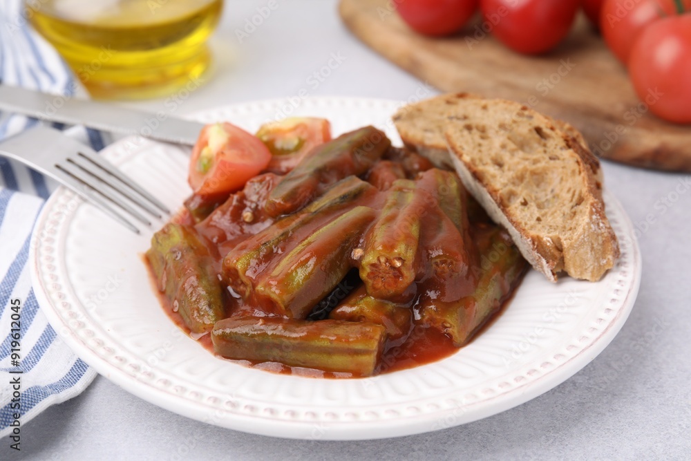 Tasty stew with okra, tomato sauce and bread on white table, closeup Tasty stew with okra, tomato sauce and bread on white table, closeup