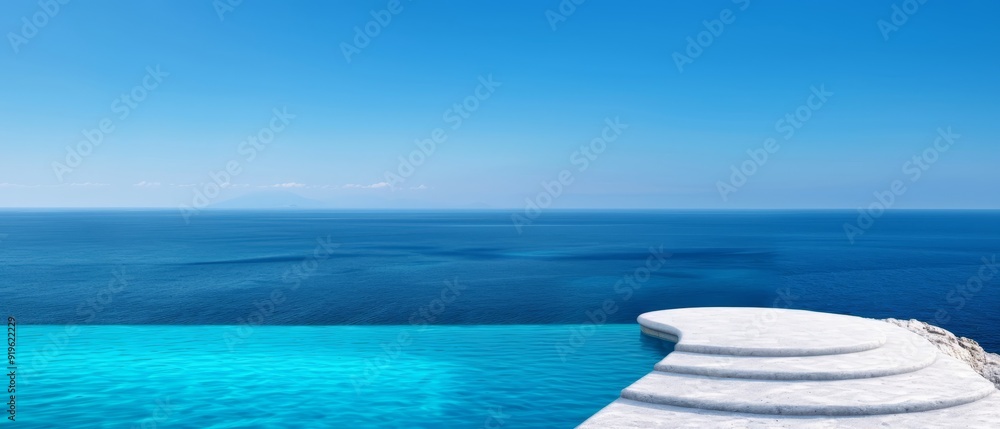 Obraz premium A clear blue sky overlooks an ocean view swimming pool, featuring steps leading up to its edge