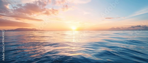  The sun sets over the ocean, painting a small island mid-frame in hues of gold, while scattered clouds tinge the sky pink and orange