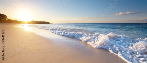  The sun sets over the ocean, waves approach the shore, a beach lies in the foreground