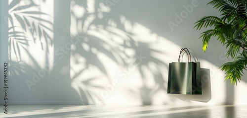 A green bag is hanging from a tree branch in front of a white wall