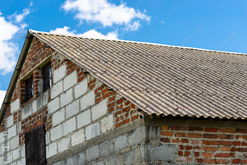 An old brick barn in the Polish countryside with a corrugated asbestos roof.