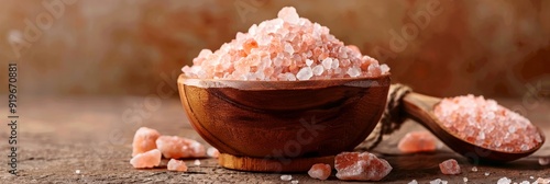 A bowl and spoon filled with pink Himalayan salt, a natural and healthy alternative to table salt. The salt is pink in color due to its high mineral content and is known for its taste and health benef photo