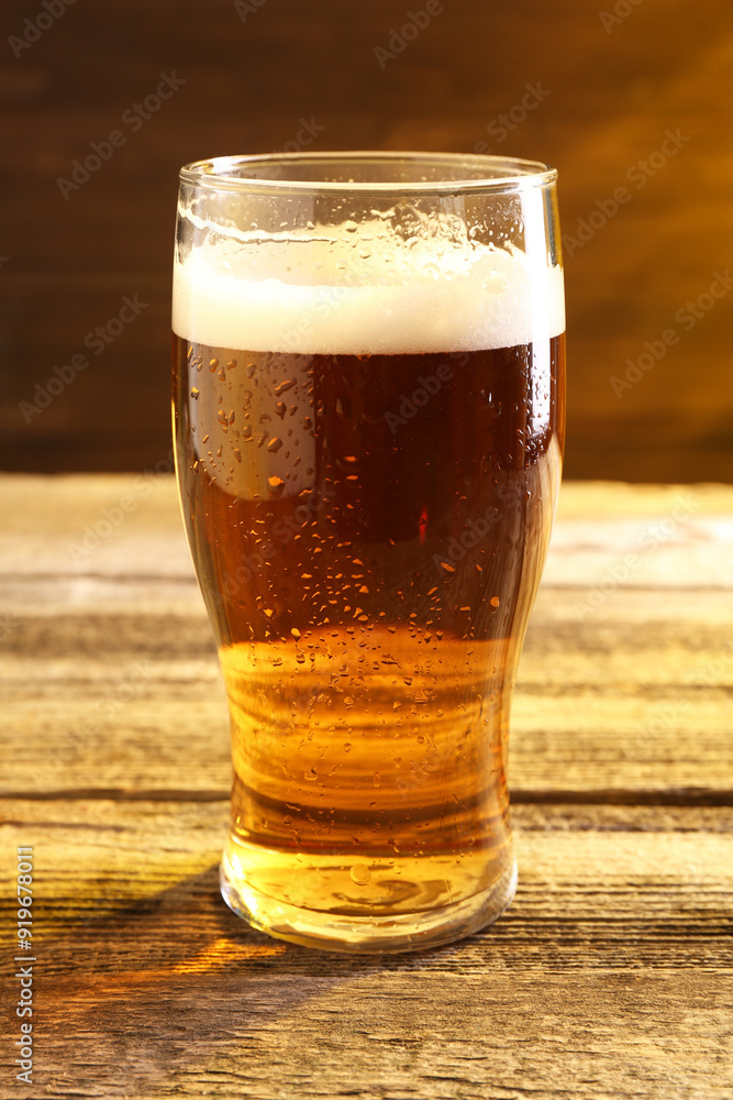 Glass of beer with froth on wooden table Glass of beer with froth on wooden table