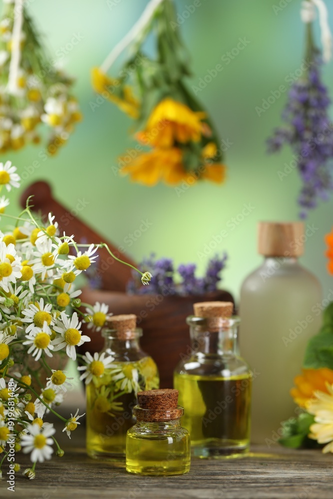 Beautiful chamomile flowers and bottles of essential oils on wooden table Beautiful chamomile flowers and bottles of essential oils on wooden table