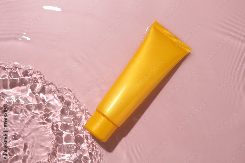 Cosmetic product. Tube with cream in water on pink background, top view Cosmetic product. Tube with cream in water on pink background, top view