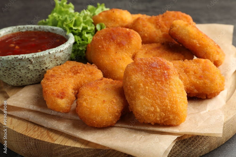 Board with hot chili sauce, lettuce and nuggets on table, closeup Board with hot chili sauce, lettuce and nuggets on table, closeup