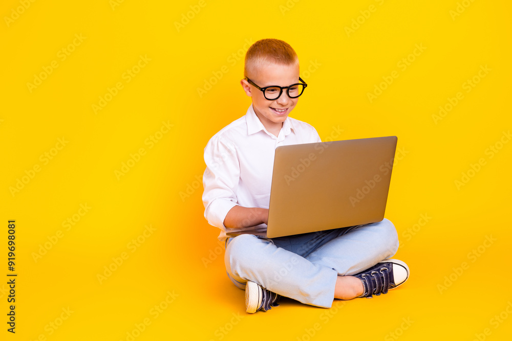 Photo of clever intelligent charming boy wear white shirt sit floor isolated on yellow color background Photo of clever intelligent charming boy wear white shirt sit floor isolated on yellow color background
