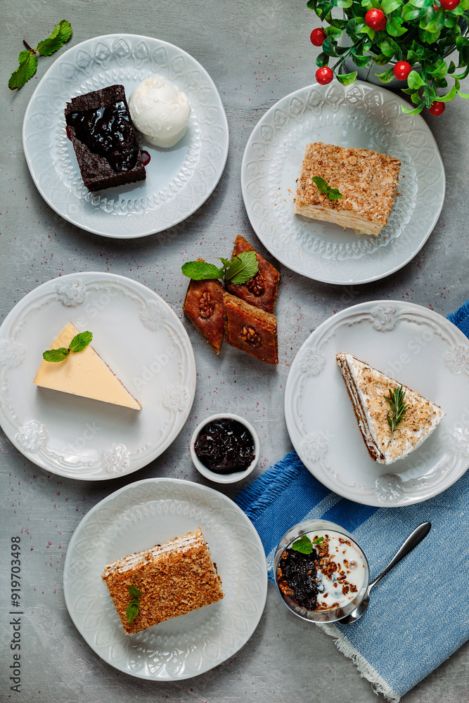Variety of desserts on white plates including baklava, honey cake, cheesecake and brownie with ice cream Variety of desserts on white plates including baklava, honey cake, cheesecake and brownie with ice cream