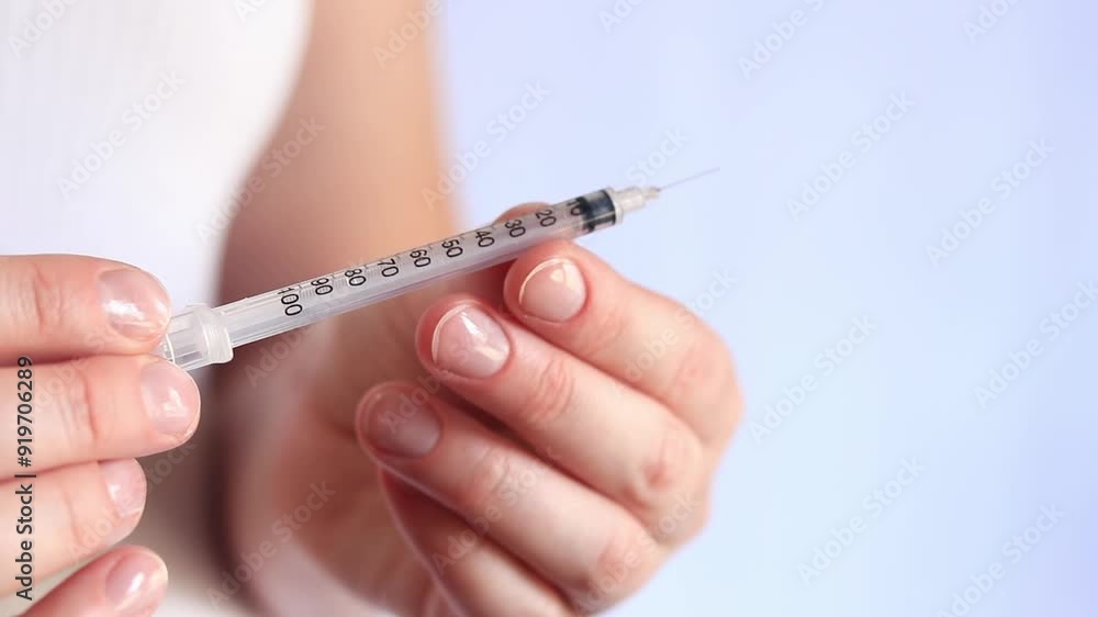 Insulin syringe. A woman's hand holds a syringe on a white background, close-up. Insulin syringe for diabetes. Diabetes treatment. Medicine and health concept Insulin syringe. A woman's hand holds a syringe on a white background, close-up. Insulin syringe for diabetes. Diabetes treatment. Medicine and health concept