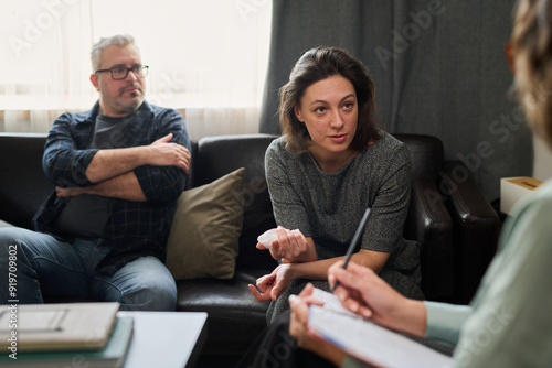 Group of individuals engaged in meaningful conversation while seated on comfortable couches in cozy room illuminated by natural light photo