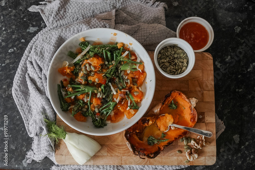 Roasted butternut squash on wooden board. Pumpkin seeds, fennel and nuts with broccoli for a super healthy vegan summer salad. Coated in dressing.