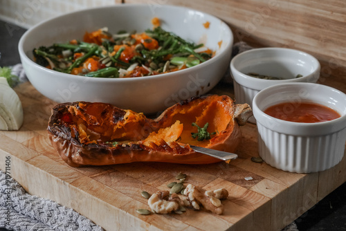 Roasted butternut squash on wooden board. Pumpkin seeds, fennel and nuts with broccoli for a super healthy vegan summer salad. Coated in dressing.