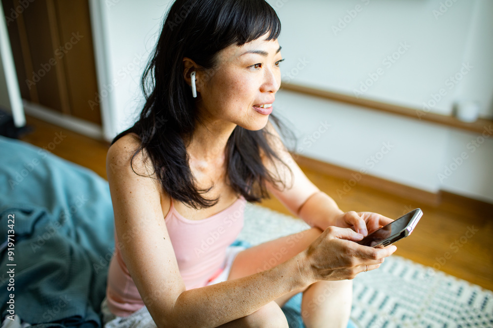 Smiling Asian woman using smartphone in bed at home Smiling Asian woman using smartphone in bed at home