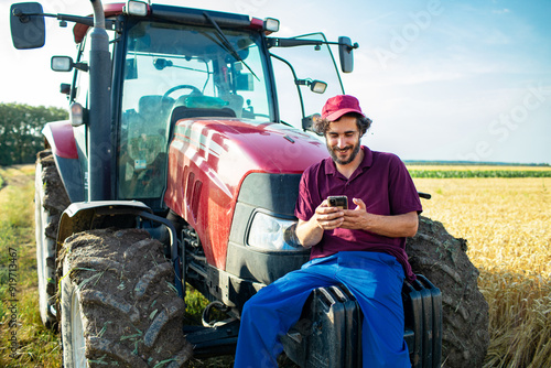 Middle aged male farmer using smartphone on tractor photo