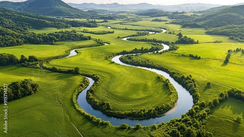 A winding river flows through a lush green valley, surrounded by rolling hills. The river creates a unique pattern as it meanders through the meadow.