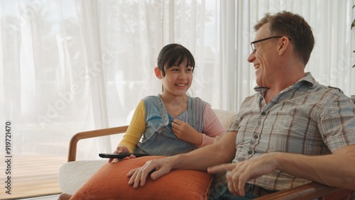 Grandfather and granddaughter together watch interesting entertainment media on TV. Old senior use technology communicate with young generation cross generation gap strengthen family bond. Divergence.