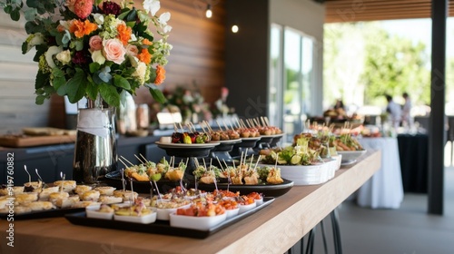 A beautifully arranged table features an array of gourmet canapes and vibrant floral centerpieces during an outdoor gathering.