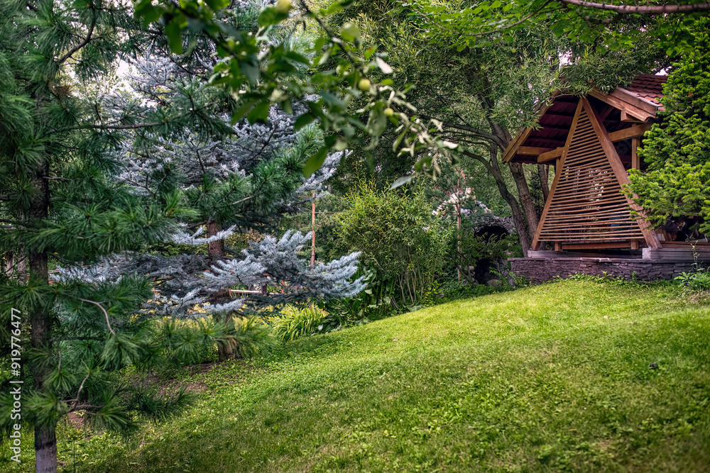 A picturesque wooden house on a green lawn in a summer green garden. A picturesque wooden house on a green lawn in a summer green garden.