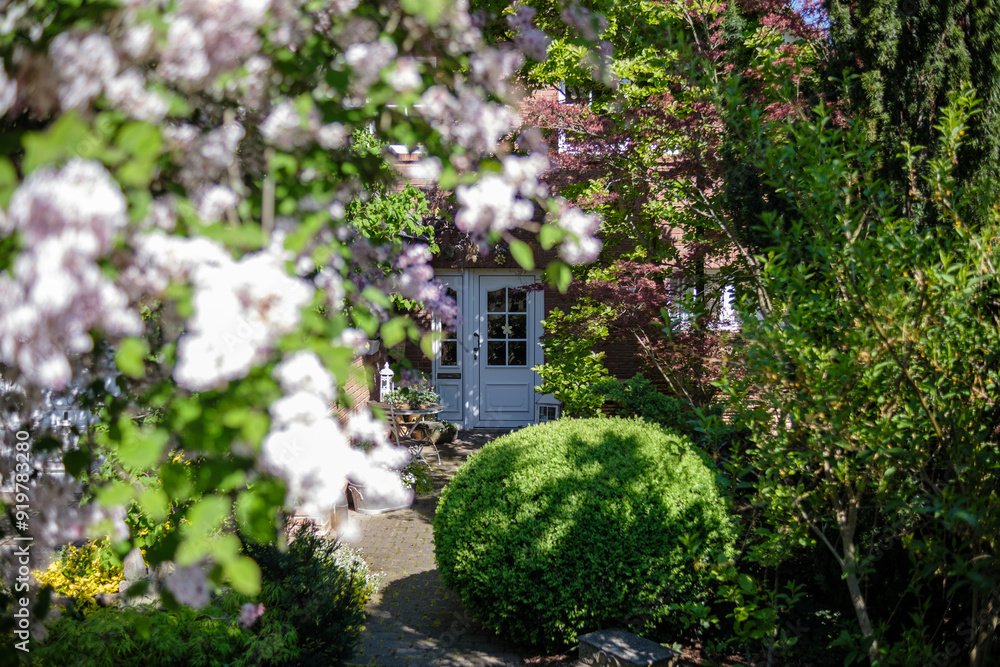 An elegant suburban house surrounded by a lush garden with blooming flowers. Germany.