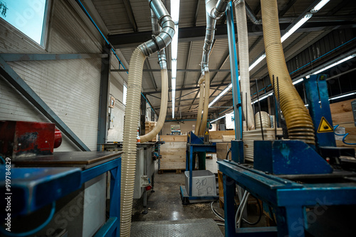 Industrial wood processing machinery with large exhaust pipes and ventilation systems in a well-lit factory interior photo