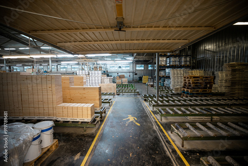 A large woodworking factory with stacks of freshly cut timber panels ready for processing, showcasing industrial efficiency and precision in a well-lit manufacturing environment photo