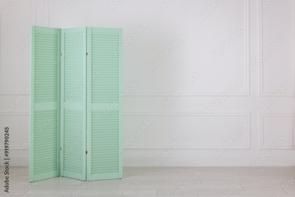 One folding screen near white wall indoors, space for text. Interior element One folding screen near white wall indoors, space for text. Interior element