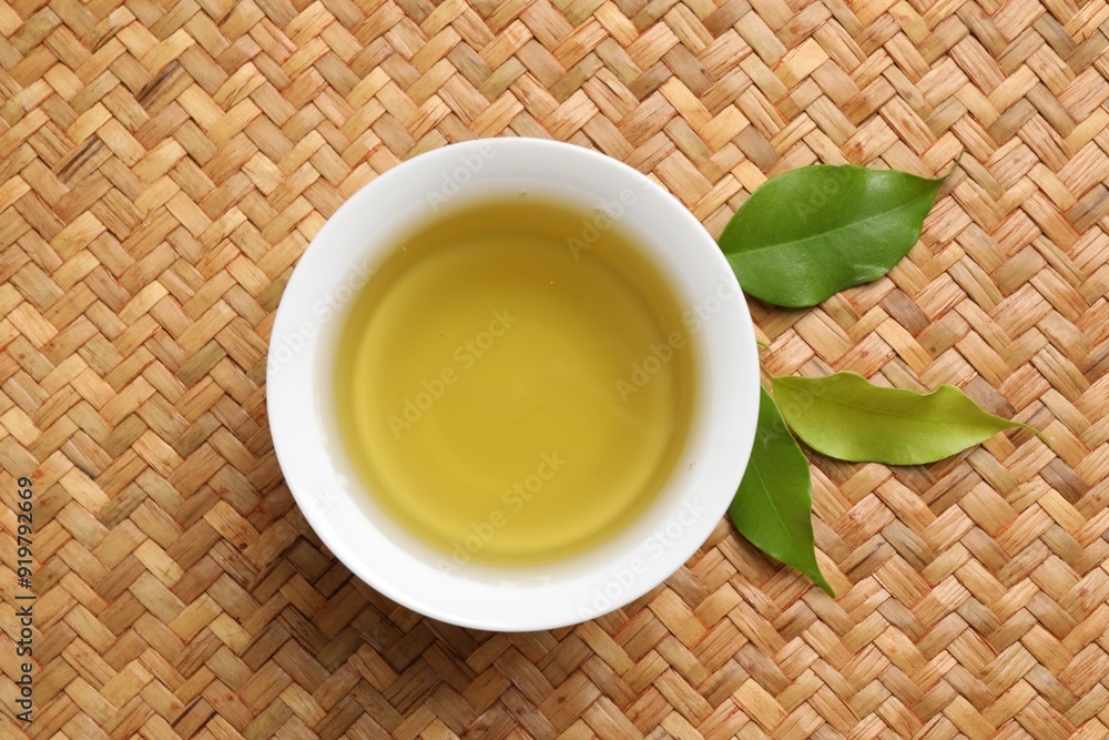 Refreshing green tea in cup and leaves on table, flat lay Refreshing green tea in cup and leaves on table, flat lay