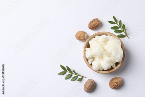 Foto Shea butter in bowl and nuts on white background, flat lay