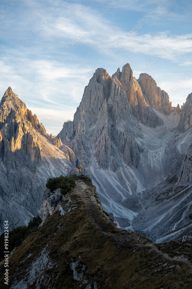 An adventurous woman hikes on a narrow ridge with majestic mountain peaks in the background, showcasing the scenic beauty of the alpine terrain. An adventurous woman hikes on a narrow ridge with majestic mountain peaks in the background, showcasing the scenic beauty of the alpine terrain.