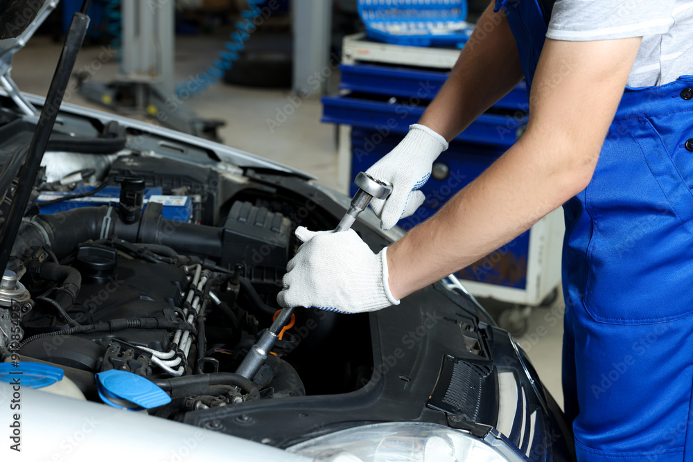 Auto mechanic fixing car at automobile repair shop, closeup Auto mechanic fixing car at automobile repair shop, closeup