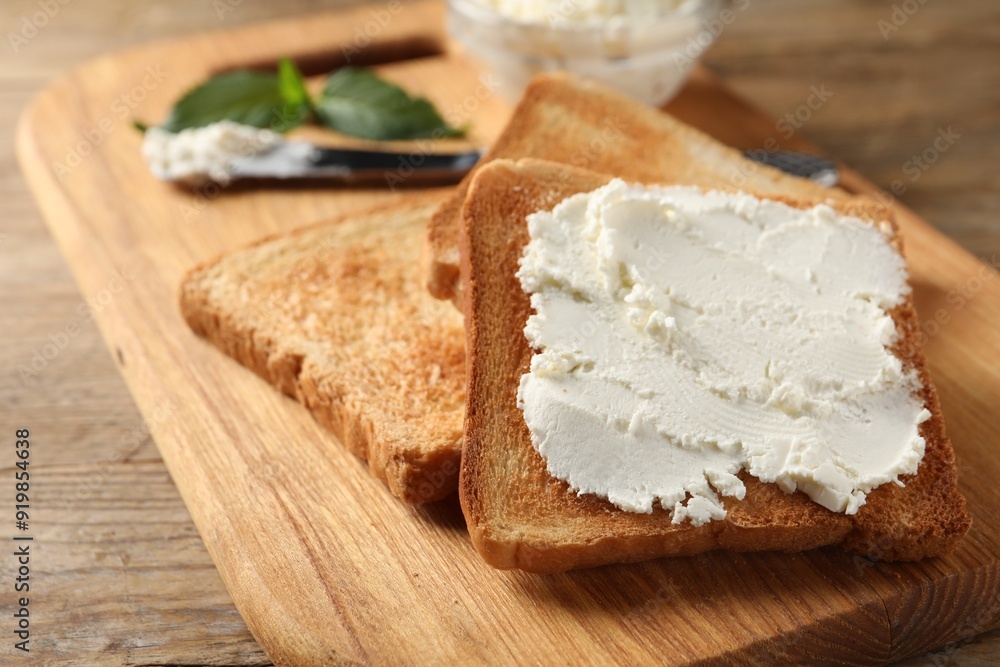 Delicious toasted bread slices with cream cheese on wooden table, closeup Delicious toasted bread slices with cream cheese on wooden table, closeup