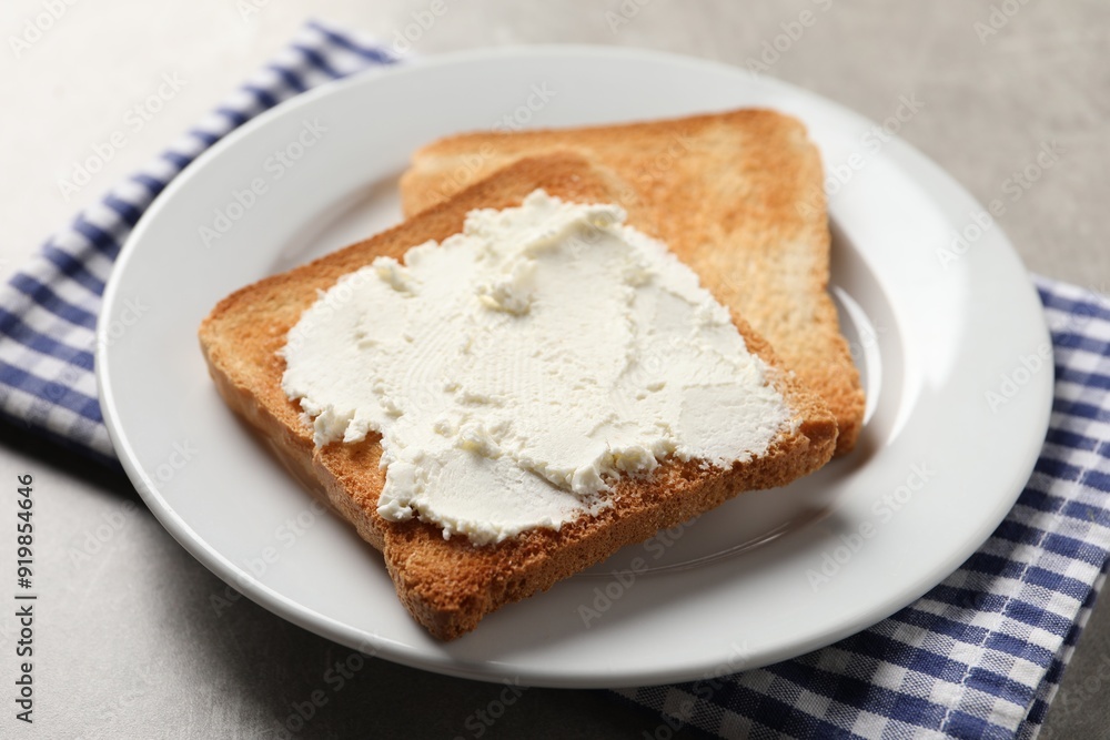Delicious toasted bread slices with cream cheese on grey table Delicious toasted bread slices with cream cheese on grey table