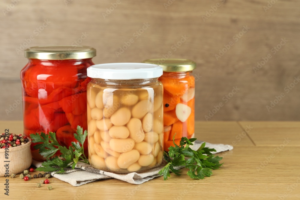 Different pickled products in jars and spices on wooden table Different pickled products in jars and spices on wooden table