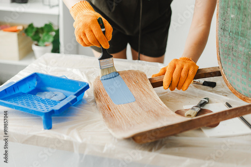 Woman restoring old furniture painting wooden surface with blue paint photo