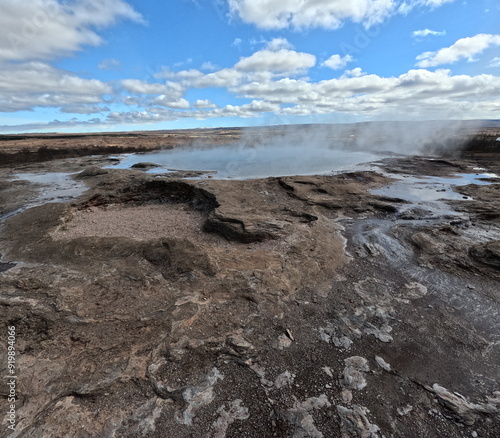 Steaming Geothermal Springs in Iceland with a Rugged Landscape and Fluffy Clouds 