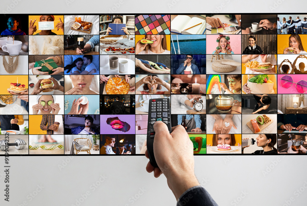 © Prostock-studio - A hand holds a black remote control in front of a large television screen displaying a variety of images in a grid format. The images showcase everyday activities, objects, and people © Prostock-studio - A hand holds a black remote control in front of a large television screen displaying a variety of images in a grid format. The images showcase everyday activities, objects, and people