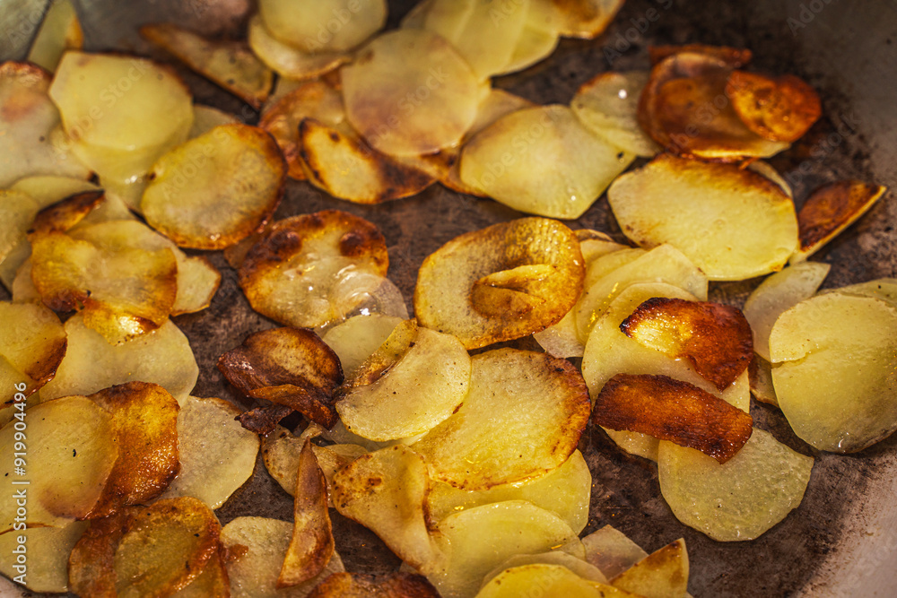 Potatoes fried in a pan until golden brown. Fried potato slices in a steel pan. Quick homemade vegetarian dish Potatoes fried in a pan until golden brown. Fried potato slices in a steel pan. Quick homemade vegetarian dish