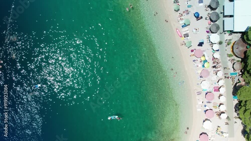 Bird's Eye View of Pristine Croatian Beach with Swimmers, Paddle Boards, and Beach Umbrellas, Baska Voda, Croatia (Ikovac  Beach) 