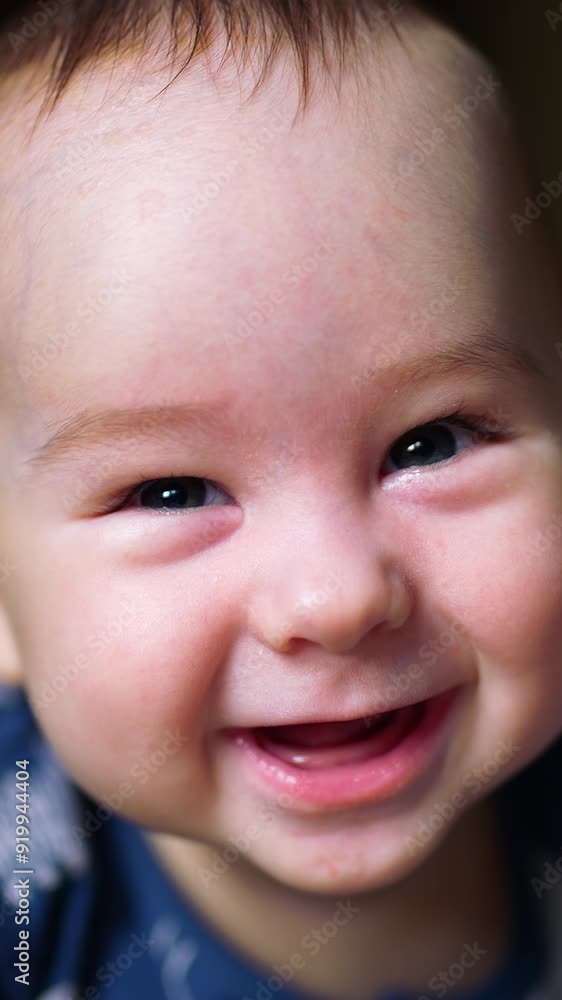 Sweet toothless smile of a beautiful baby boy. Little child lies on his belly holding head up and looking into camera. Close up. Vertical video Sweet toothless smile of a beautiful baby boy. Little child lies on his belly holding head up and looking into camera. Close up. Vertical video