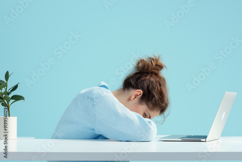 Exhausted woman resting her head on desk, surrounded by laptop and stationery, depicting burnout, stress, and fatigue in modern work environment.