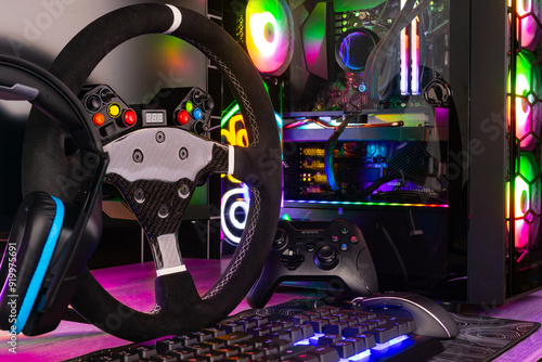 colorful gaming pc desk with bright raimbow led computer gamepad mouse keyboard and steering wheel. esports video games concept background photo