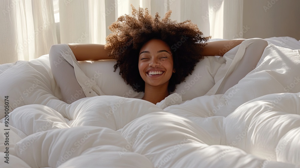 A woman is smiling and laying on a bed with a pillow. The bed is covered in white sheets and the woman is wearing a white shirt A woman is smiling and laying on a bed with a pillow. The bed is covered in white sheets and the woman is wearing a white shirt