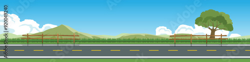 Horizontal view of Asphalt road.  Background of green grass with  Wooden fence. Hills with mountain under the white clouds and blue sky.